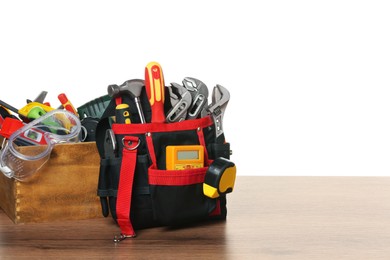 Photo of Crate and bag with tools on wooden table against white background