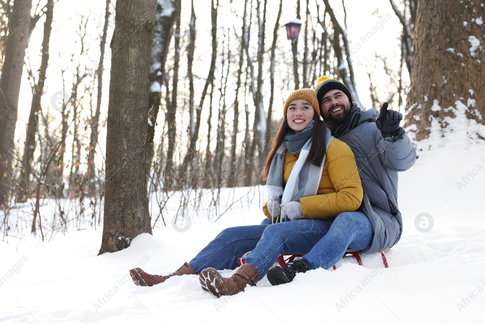 Photo of Happy young couple sledding outdoors on winter day