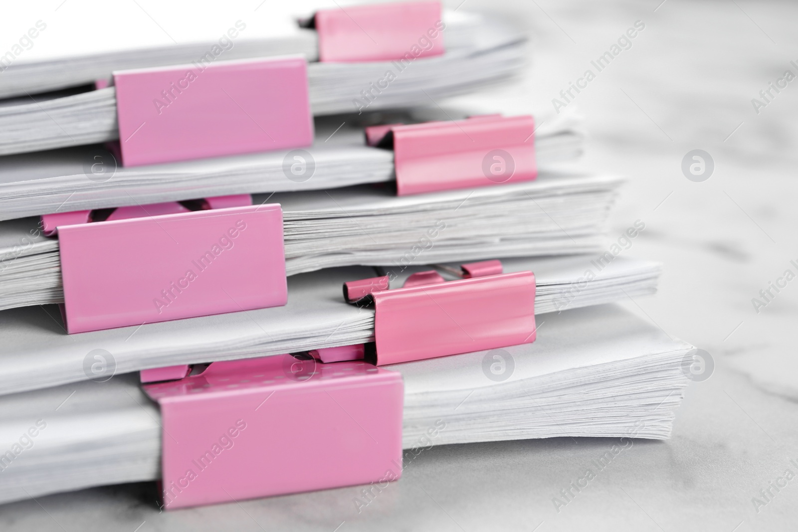 Photo of Stack of documents with binder clips on marble table, closeup