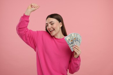 Happy woman with dollar banknotes on pink background