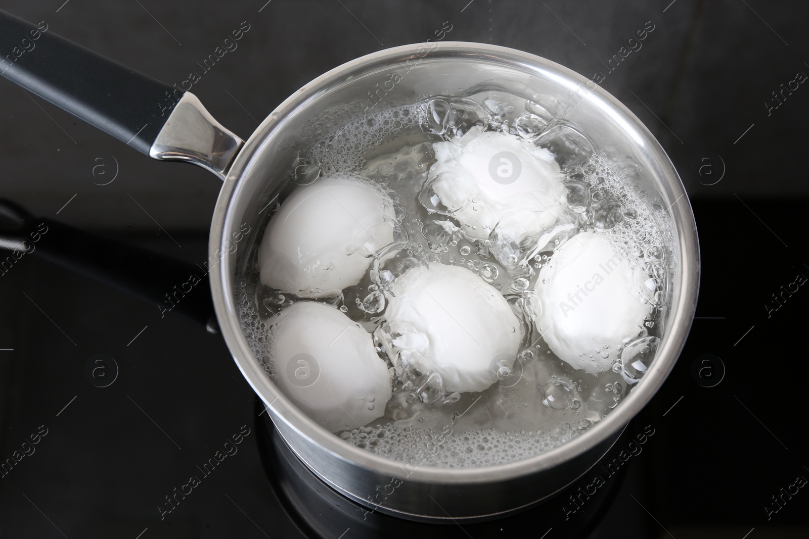 Photo of Chicken eggs boiling in saucepan on electric stove, above view