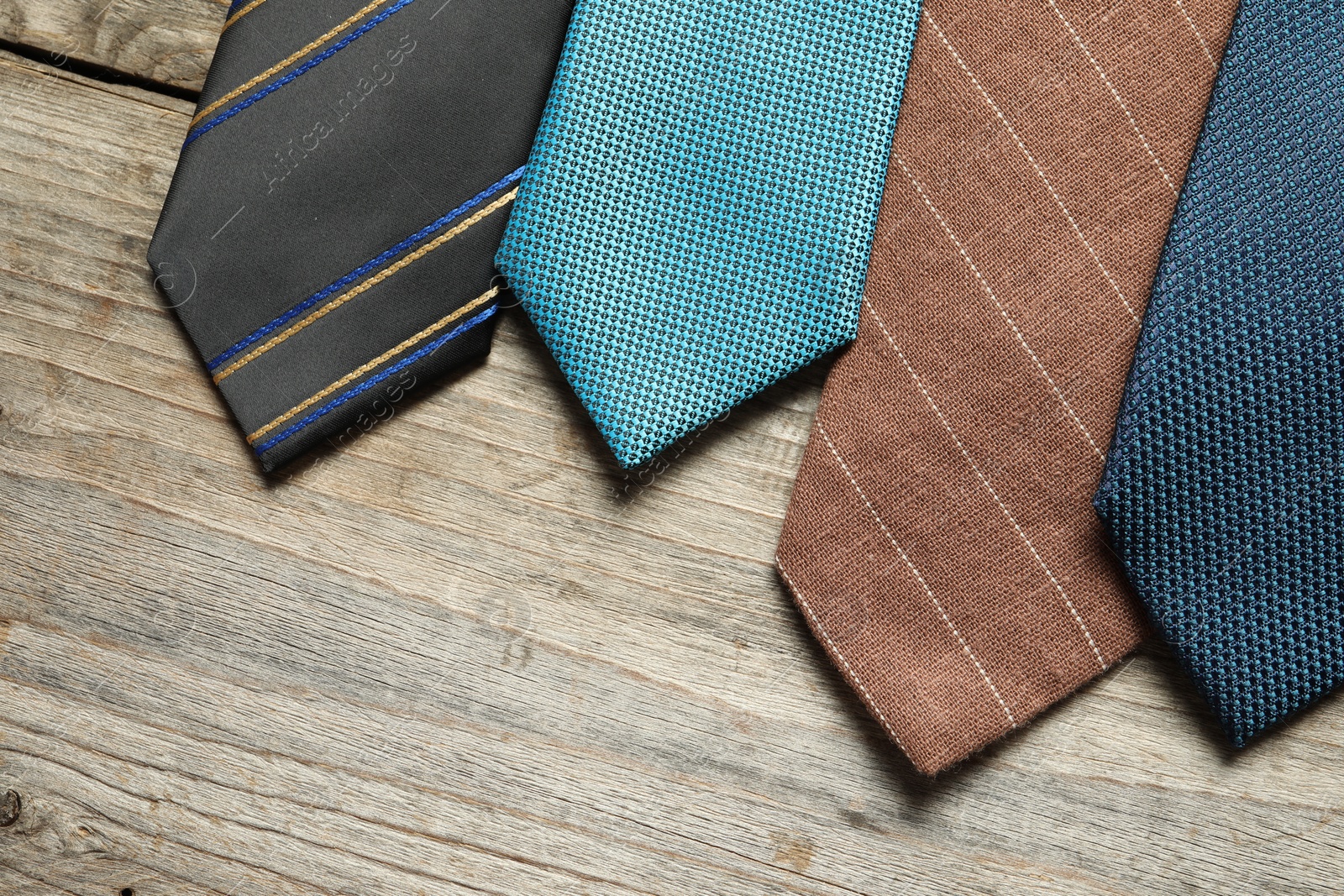 Photo of Different neckties on light wooden table, flat lay