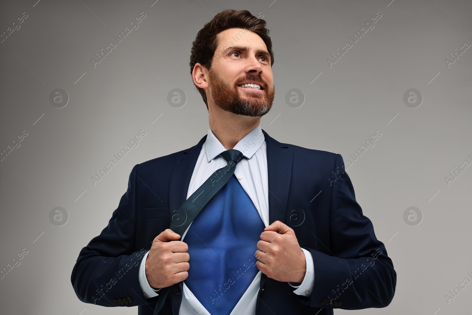 Image of Happy businessman wearing superhero costume under suit on light grey background