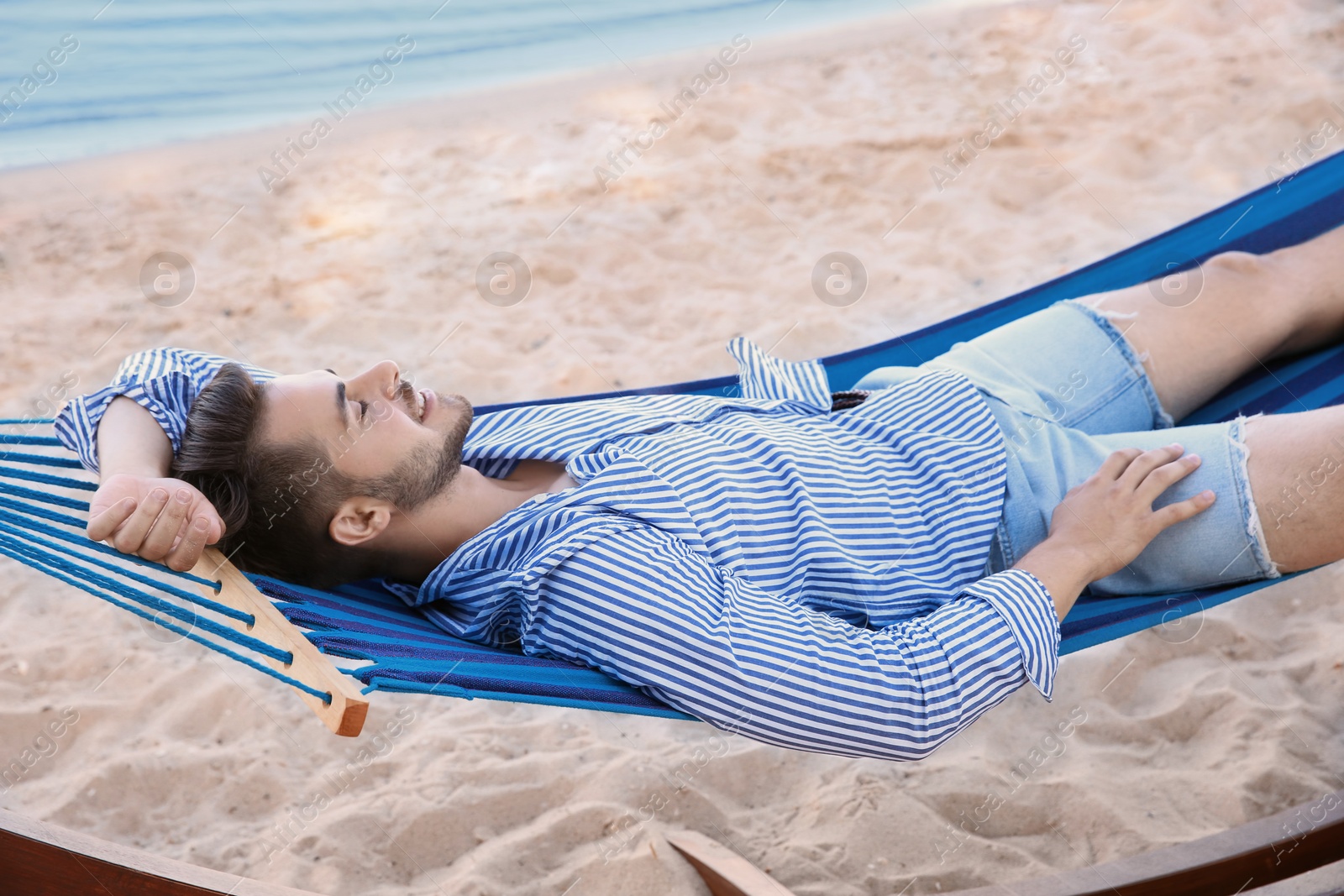 Photo of Young man resting in hammock at seaside. Summer vacation