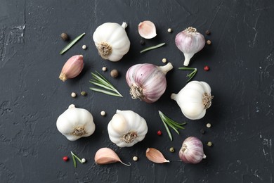 Photo of Fresh garlic, rosemary and peppercorns on dark textured table, flat lay