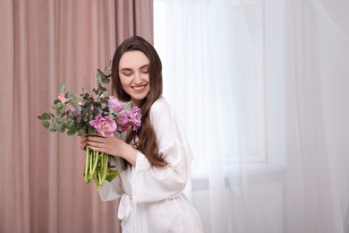 Photo of Beautiful happy young woman with bouquet of flowers indoors