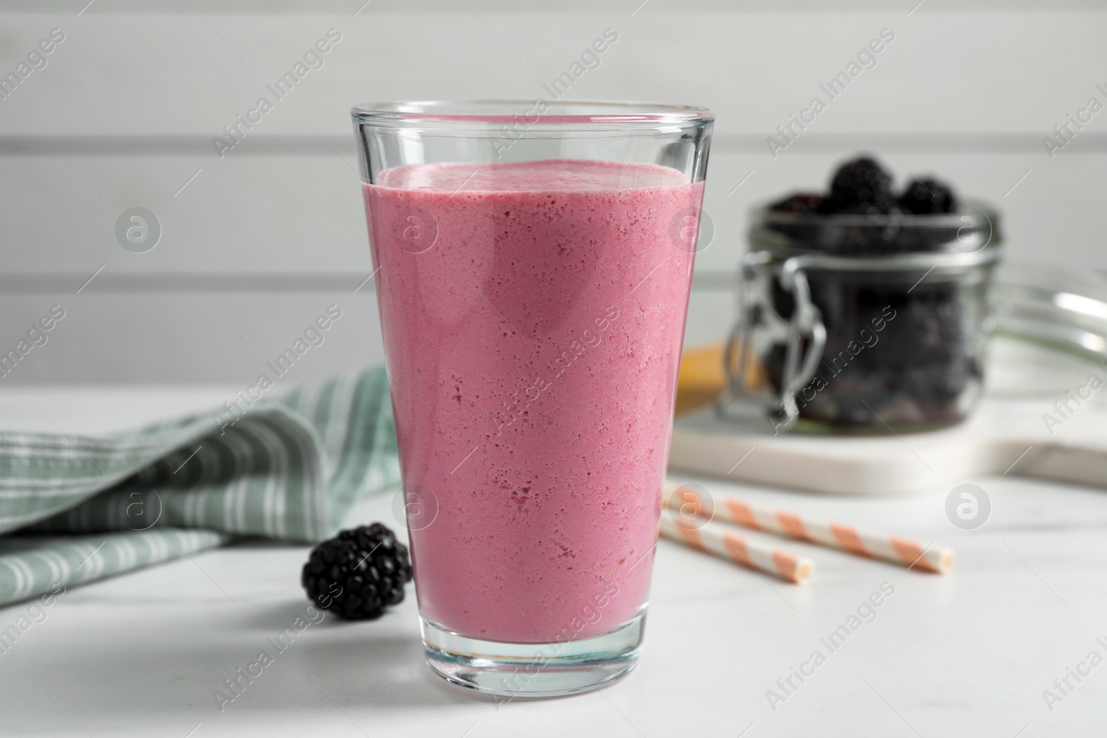 Photo of Glass of blackberry smoothie on white table