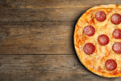 Photo of Tasty pepperoni pizza on wooden table, top view. Space for text