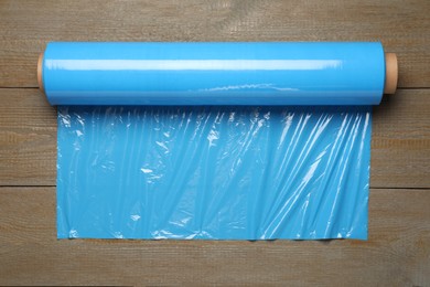 Photo of Roll of plastic stretch wrap film on wooden table, top view