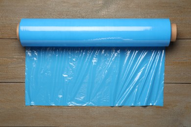 Roll of plastic stretch wrap film on wooden table, top view