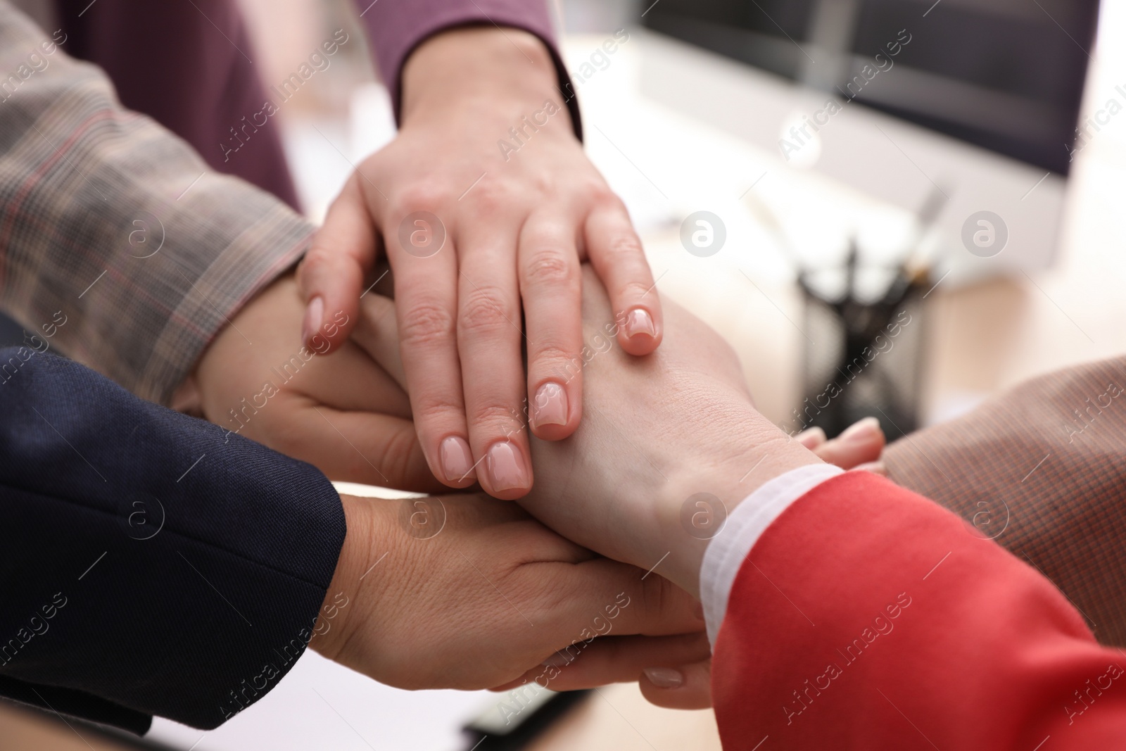 Photo of Women holding hands together in office, closeup