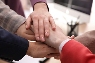 Photo of Women holding hands together in office, closeup