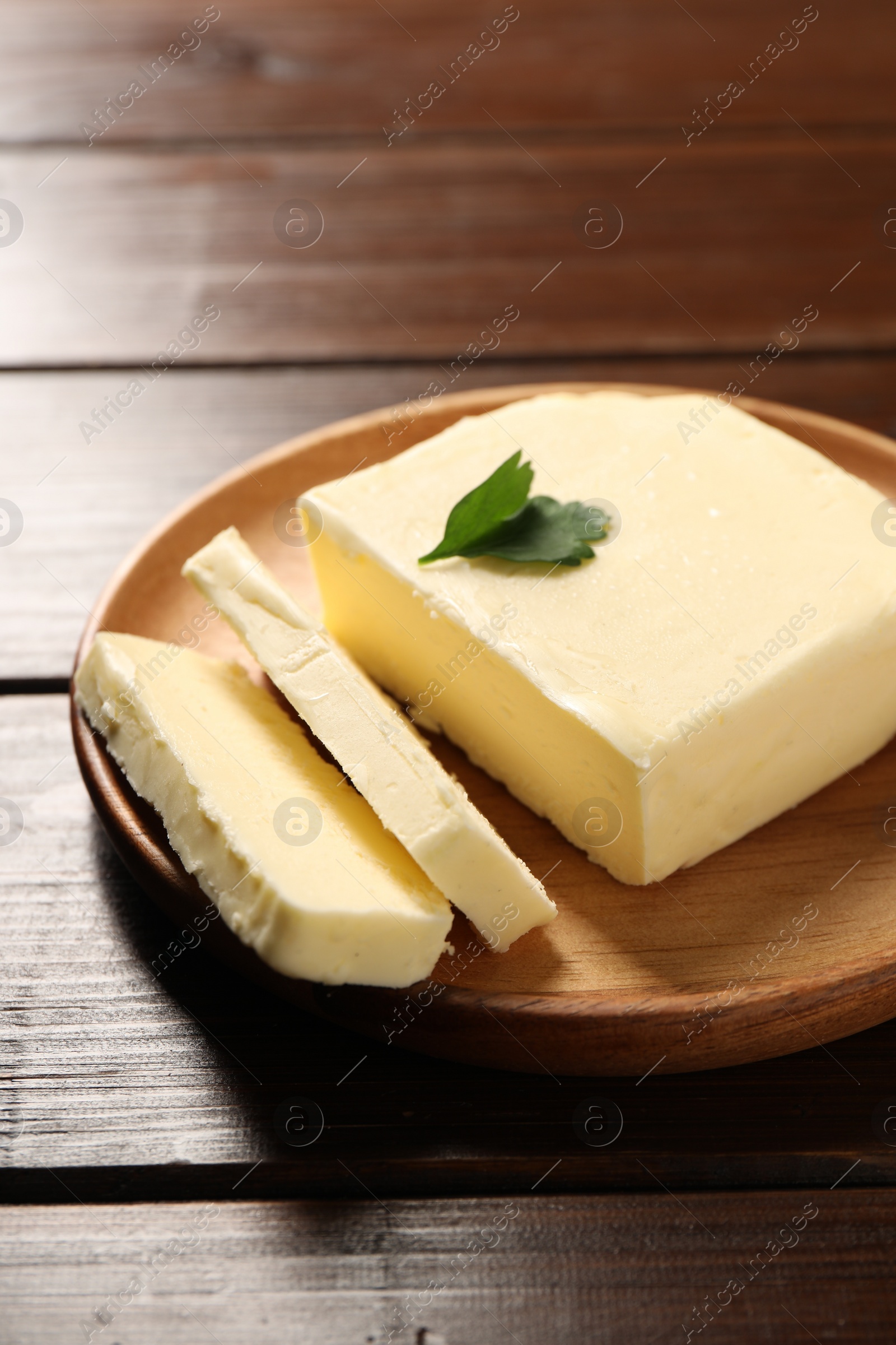 Photo of Cut tasty butter with parsley on wooden table