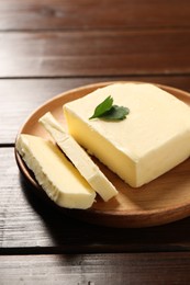 Cut tasty butter with parsley on wooden table