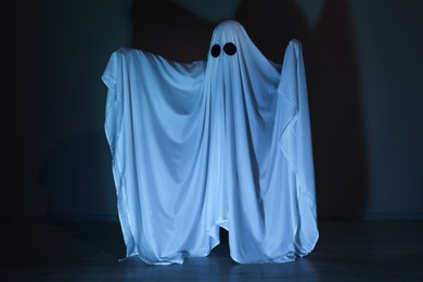 Photo of Creepy ghost. Woman covered with sheet in color light