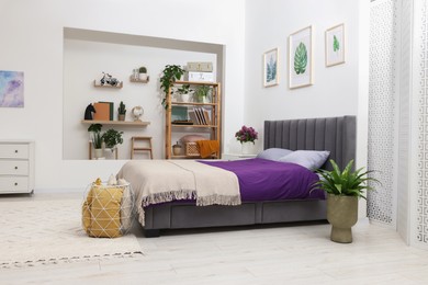 Photo of Stylish bedroom with comfortable bed, houseplants and different decor. Interior design
