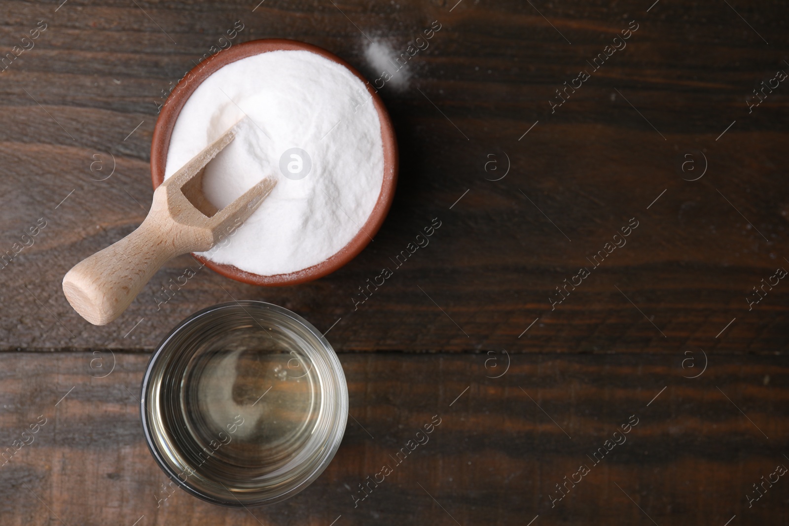 Photo of Vinegar in glass and baking soda on wooden table, top view