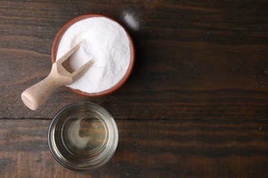 Vinegar in glass and baking soda on wooden table, top view