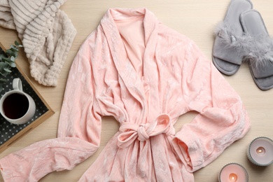 Flat lay composition with fluffy slippers and robe on wooden background. Comfortable home outfit