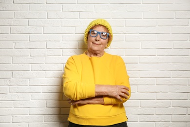 Photo of Portrait of elderly woman in hipster outfit near brick wall