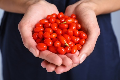 Photo of Woman holding fresh goji berries, closeup view