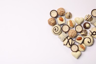 Photo of Heart made with delicious chocolate candies on white background, top view