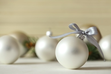 Beautiful Christmas ball on white table against blurred background. Space for text
