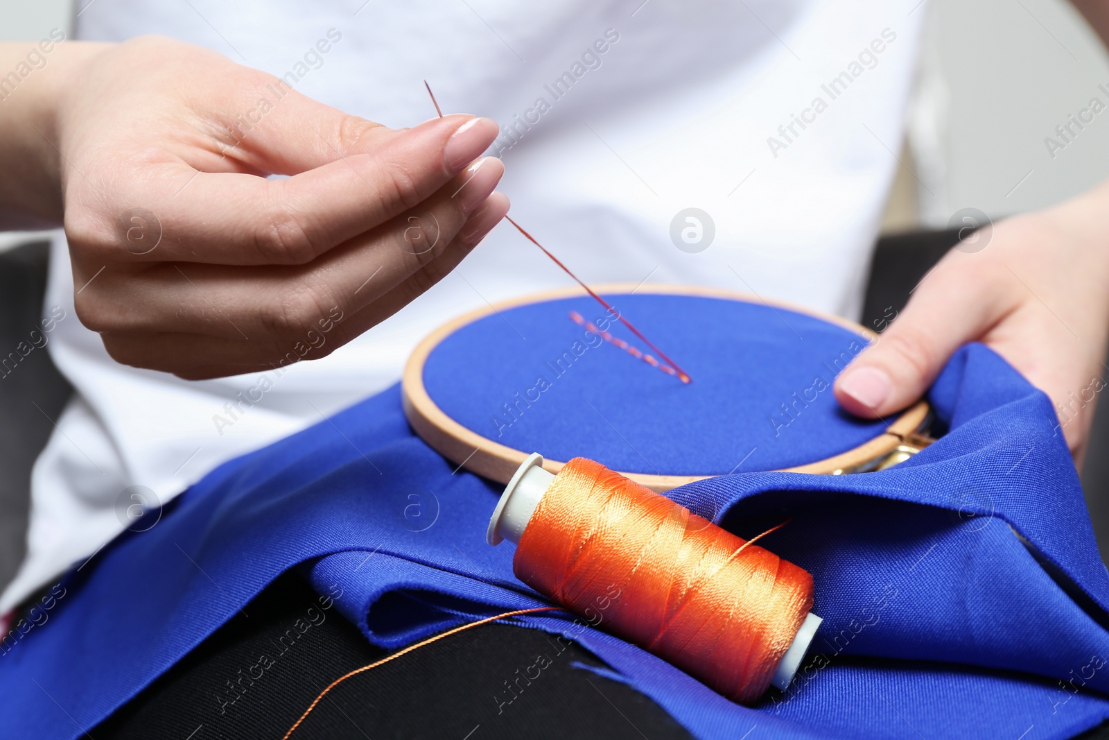 Photo of Woman with sewing needle and thread embroidering on cloth, closeup