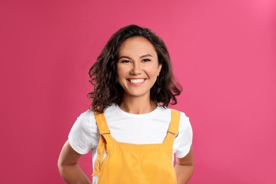 Happy young woman in casual outfit on pink background