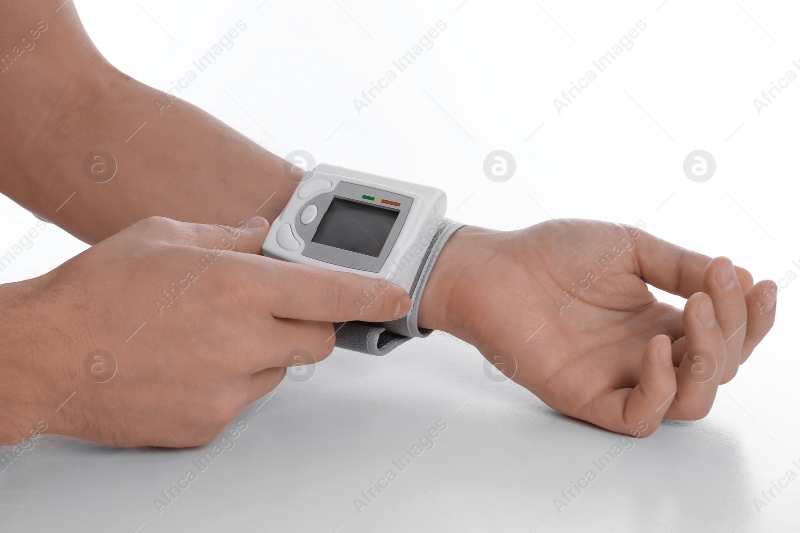 Photo of Man checking blood pressure with sphygmomanometer at table against white background, closeup. Cardiology concept