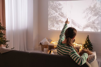 Mother and son watching Christmas movie via video projector at home