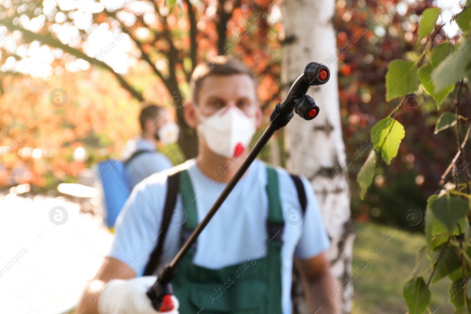 Photo of Pest control worker outdoors, focus on insecticide sprayer