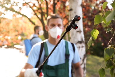 Photo of Pest control worker outdoors, focus on insecticide sprayer