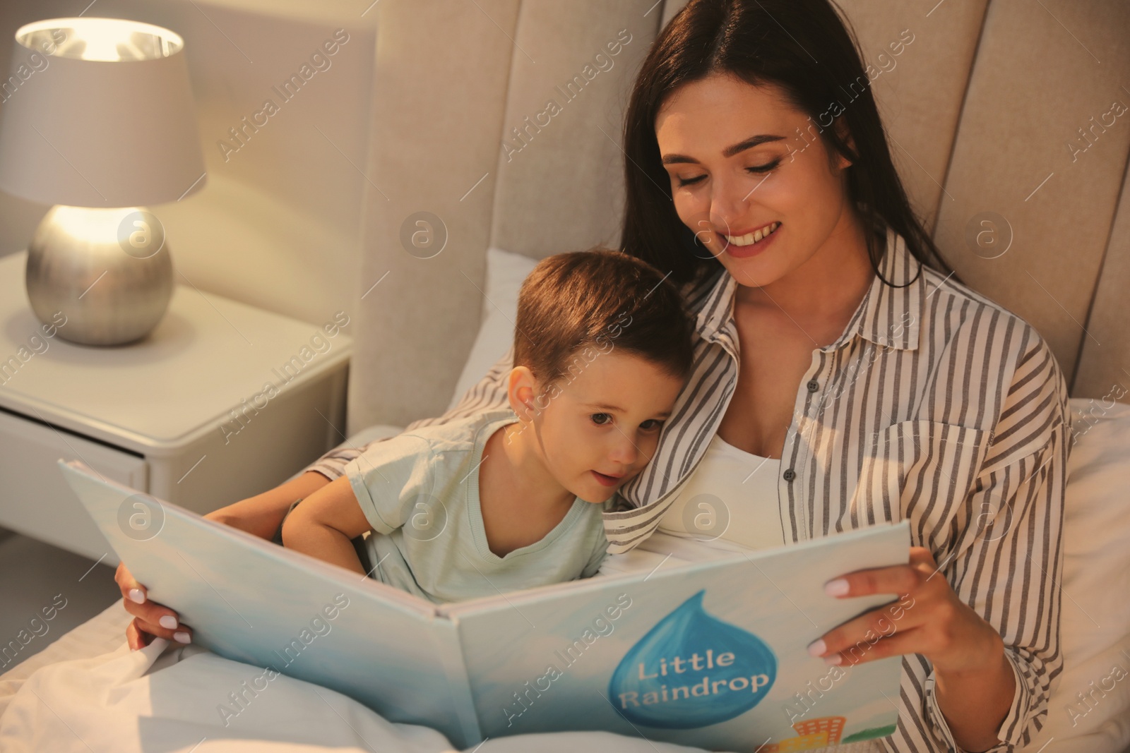 Photo of Mother reading bedtime story to her son at home