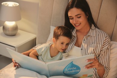 Photo of Mother reading bedtime story to her son at home