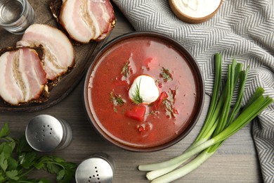 Photo of Clay bowl with Ukrainian borsch served on wooden table, flat lay