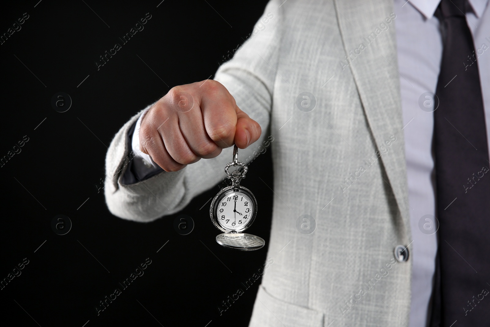 Photo of Businessman holding pocket watch on black background, closeup. Time management