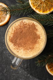 Photo of Glass cup of delicious eggnog with cinnamon and dried orange slices on gray table, flat lay