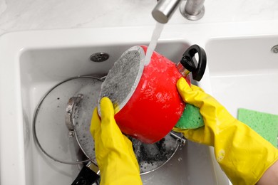 Woman washing dirty dishes in kitchen sink, closeup