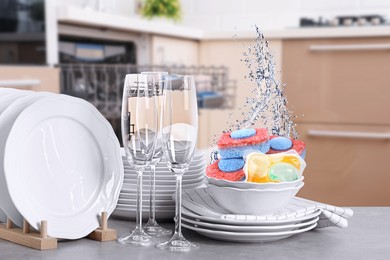 Image of Many clean tableware in kitchen. Dishwasher detergents falling into bowl with water