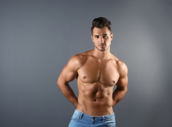 Photo of Shirtless young man in stylish jeans on grey background