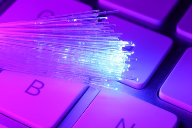 Photo of Optical fiber strands transmitting color light on computer keyboard, macro view