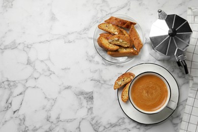 Flat lay composition with tasty cantucci and aromatic coffee on white marble table, space for text. Traditional Italian almond biscuits