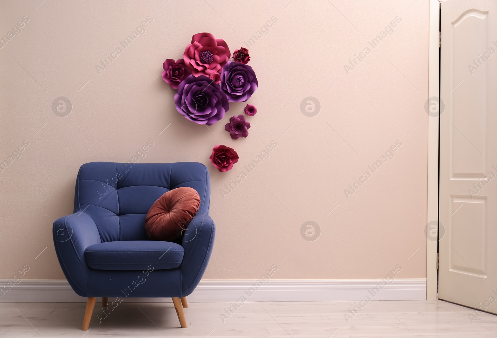Photo of Comfortable armchair near wall with floral decor in room, space for text. Interior design