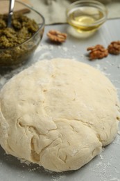 Photo of Making delicious pesto bread. Raw dough on grey table, closeup