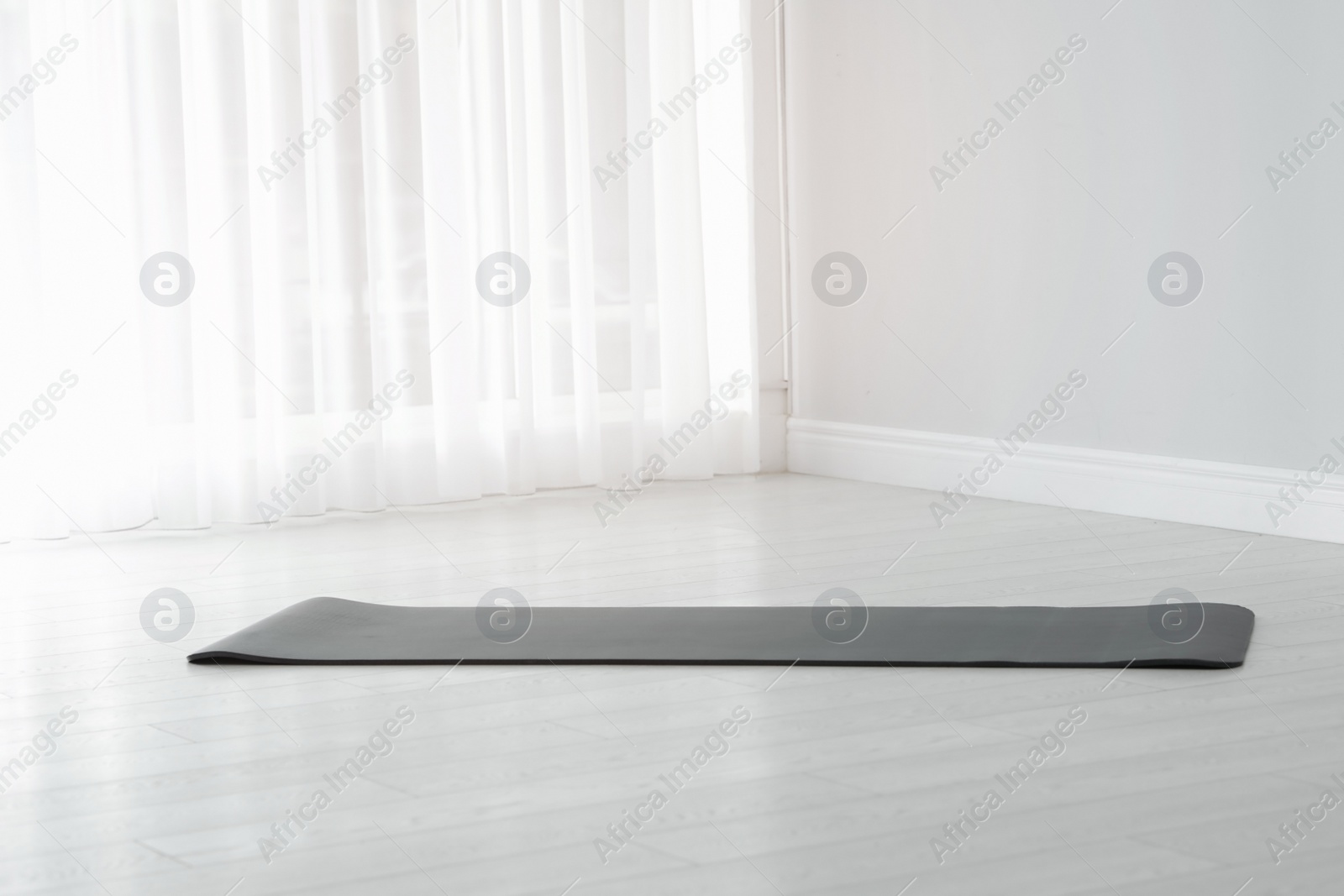 Photo of Rubber yoga mat on floor indoors. Space for text