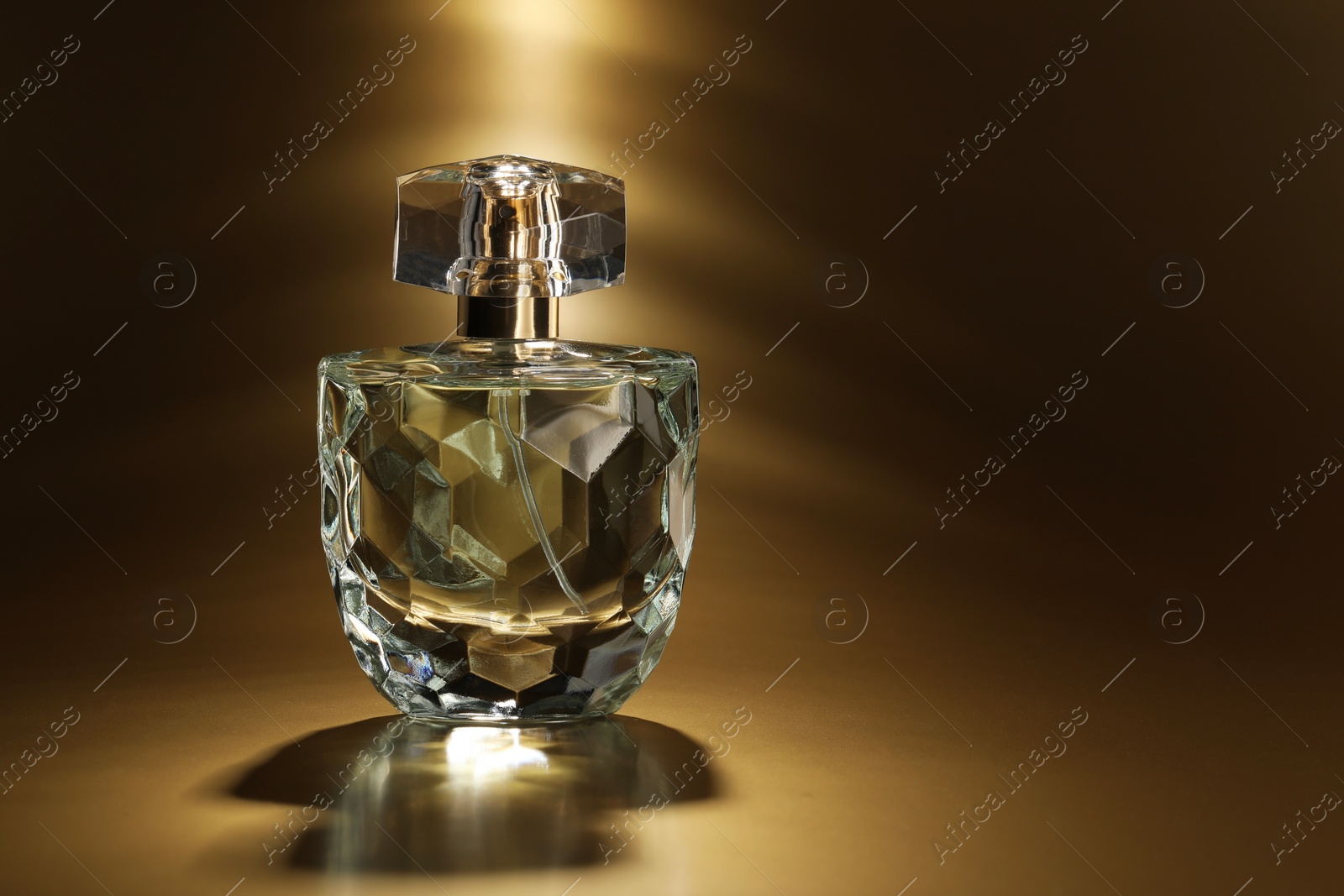 Photo of Luxury women's perfume. Sunlit glass bottle on golden background, space for text