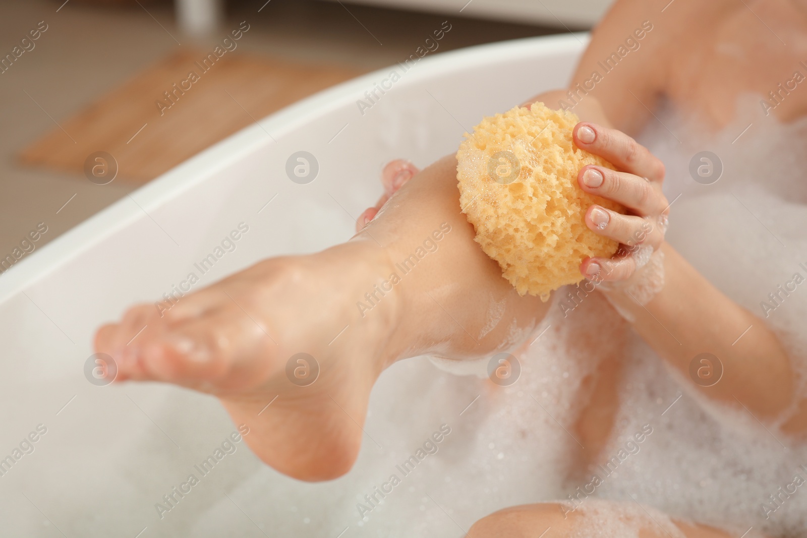 Photo of Woman with sponge taking bubble bath, closeup