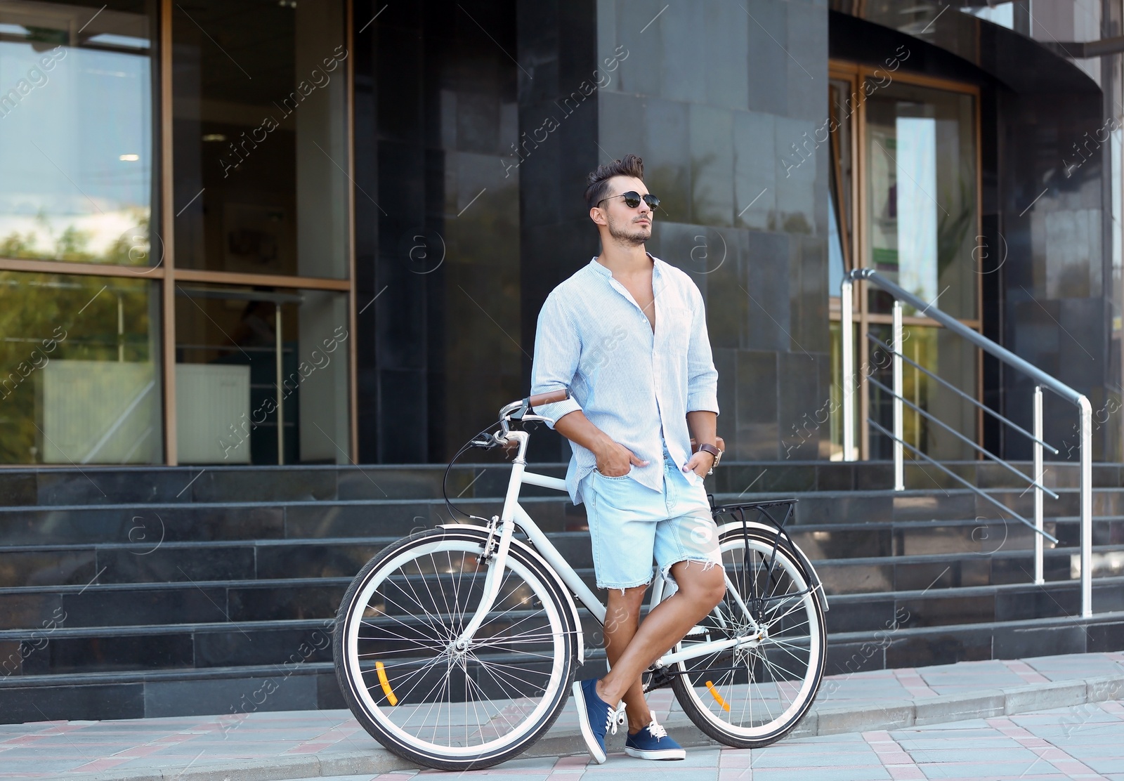 Photo of Handsome young hipster man with bicycle outdoors