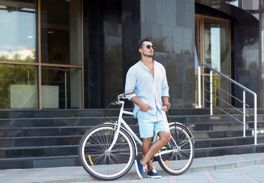 Handsome young hipster man with bicycle outdoors